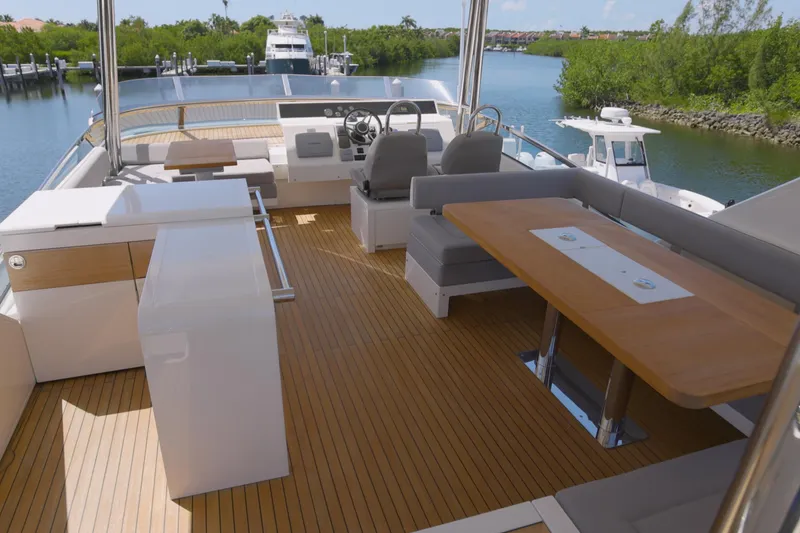 Slide: The Image of Luxurious 2014 Fairline Squadron 78 Custom yacht deck with seating and helm, docked by lush greenery. - 17
