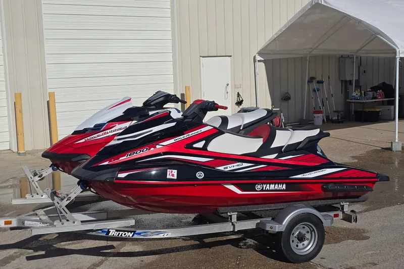 Slide: The Image of 2019 Yamaha WaveRunner GP1800R SVHO jet skis on a trailer outside a garage. - 2