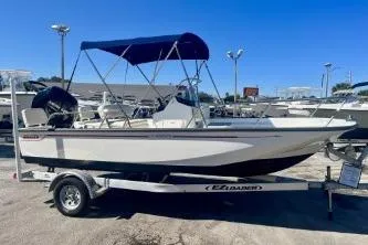 Slide: The Image of 2023 Boston Whaler 170 Montauk boat on trailer with blue canopy in a marina. - 2