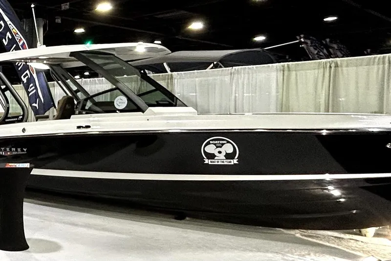 Slide: The Image of 2026 Monterey Elite 25 OB boat displayed indoors, featuring sleek black and white design. - 7