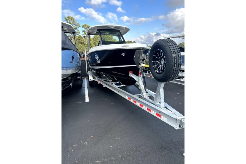 Slide: The Image of 2026 Monterey Elite 25 OB boat on trailer, parked outdoors under a partly cloudy sky. - 8