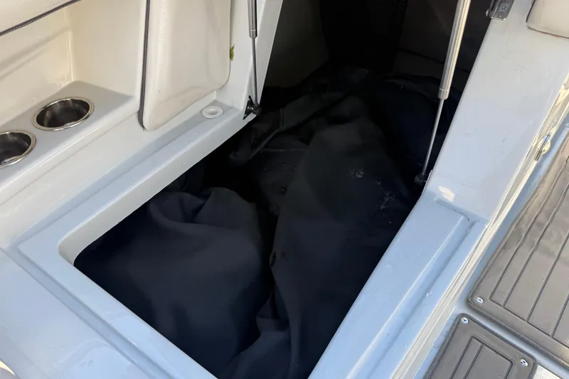 Slide: The Image of 2019 Crownline Eclipse E255 XS boat storage compartment with black cover and cup holders. - 37