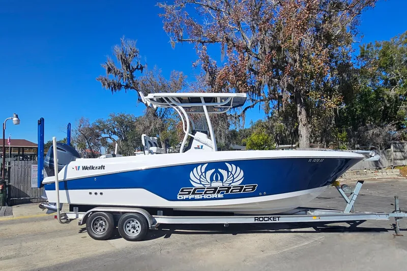 Slide: The Image of 2021 Wellcraft 242 Fisherman boat on trailer, blue and white design, parked outdoors. - 2