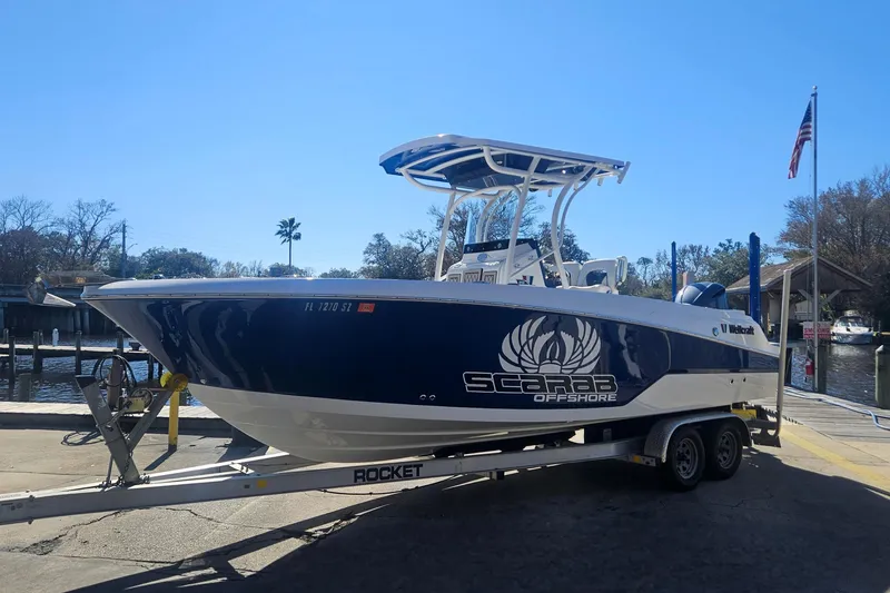 Slide: The Image of 2021 Wellcraft 242 Fisherman boat on trailer, Scarab Offshore branding, sunny day at marina. - 7