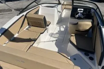 Slide: The Image of 2024 Sea Ray SPX 210 Outboard boat interior with beige seating and modern dashboard. - 8