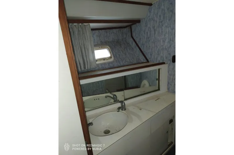 Slide: The Image of 1977 Bertram 46 Convertible yacht bathroom with sink, mirror, and porthole window. - 10