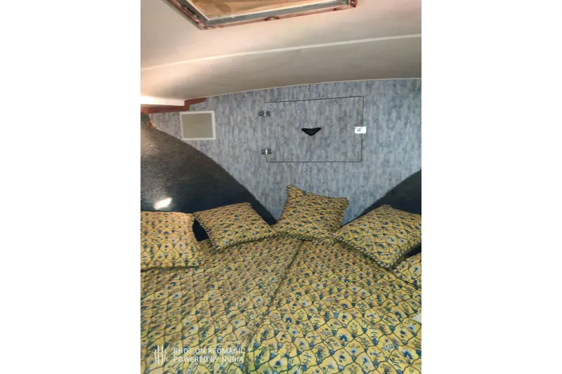 Slide: The Image of Cozy cabin interior of 1977 Bertram 46 Convertible with patterned bedding and soft lighting. - 11