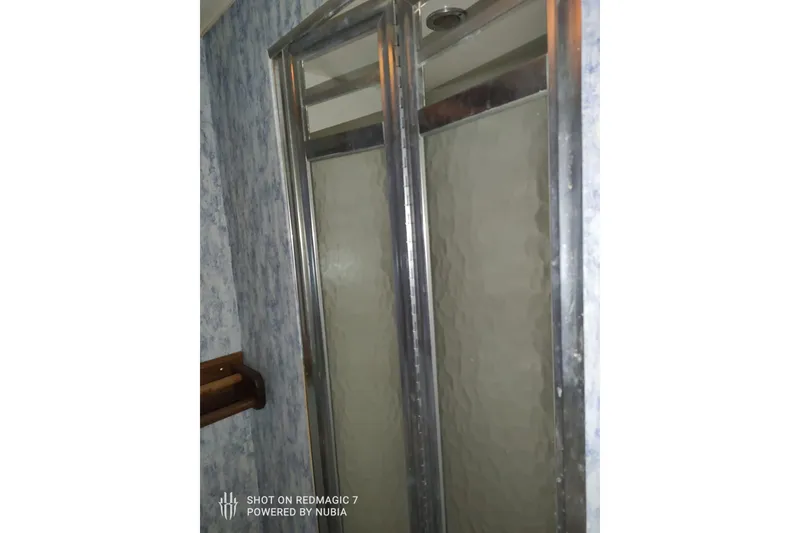 Slide: The Image of Shower area inside a 1977 Bertram 46 Convertible boat, featuring glass doors and textured walls. - 8