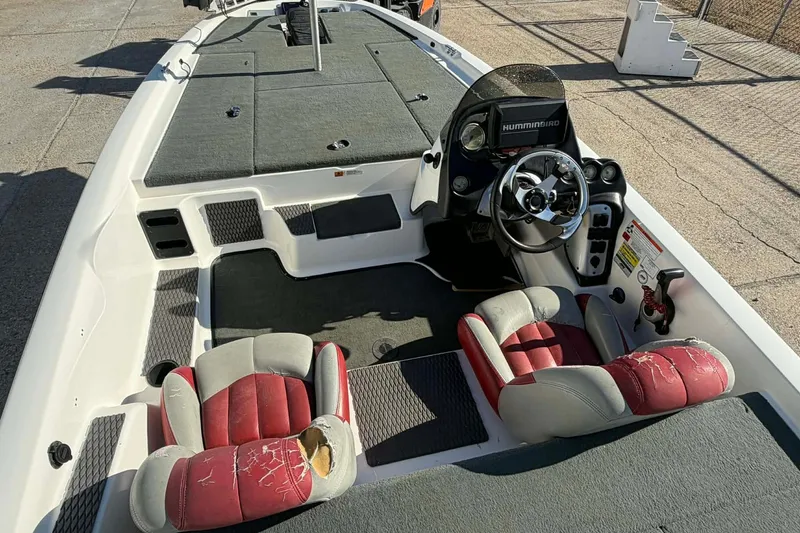 Slide: The Image of 2008 Stratos 285 XL boat interior with worn red and gray seats, steering console, and carpeted deck. - 8