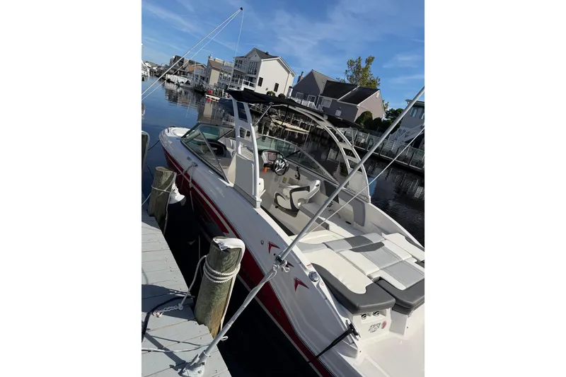 Slide: The Image of 2024 Chaparral 23 SSi OB boat docked in a scenic waterfront setting. - 2