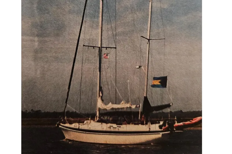 The Image of 1975 Morgan Out Island 51 sailboat anchored on calm blue water under clear sky. - 0