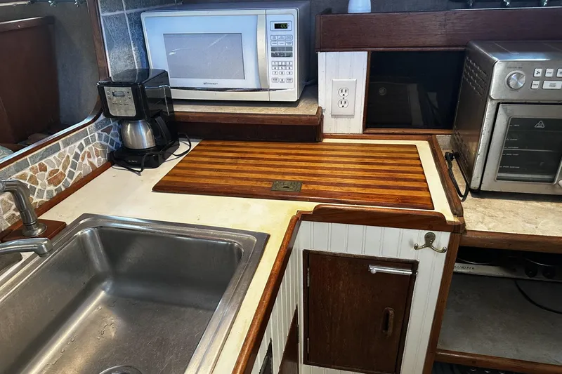 Slide: The Image of 1975 Morgan Out Island 51 yacht kitchen with sink, microwave, coffee maker, and wooden countertop. - 21