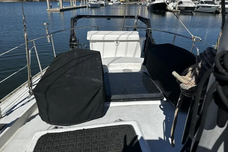 Slide: The Image of 1975 Morgan Out Island 51 sailboat deck at marina, featuring covered equipment and mooring ropes. - 56