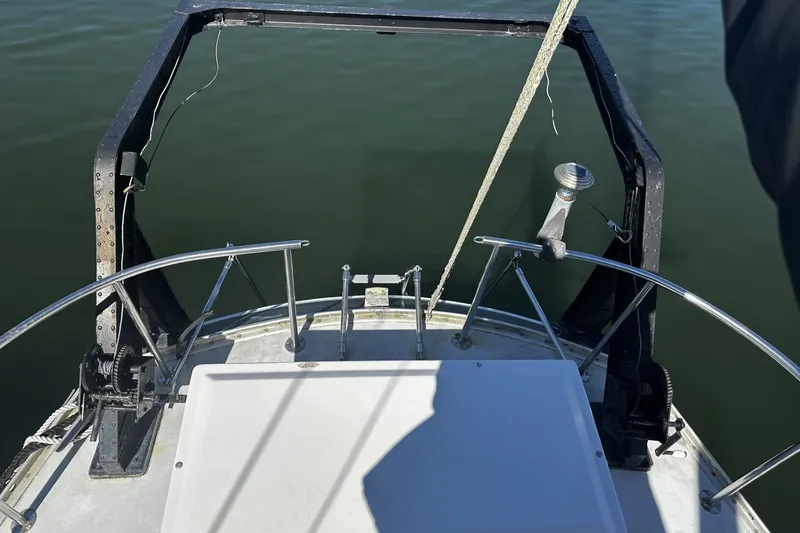 Slide: The Image of 1975 Morgan Out Island 51 sailboat deck with railing and winch, overlooking calm water. - 58