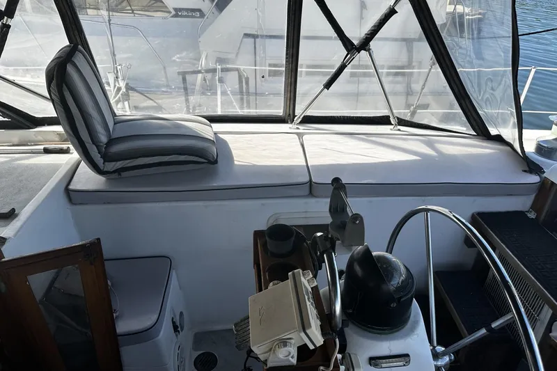 Slide: The Image of 1975 Morgan Out Island 51 cockpit with striped cushions and steering wheel, docked at marina. - 68