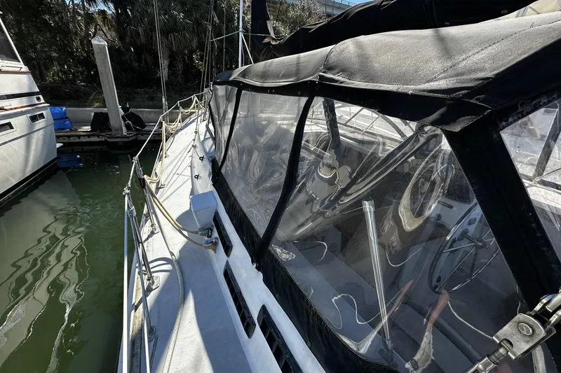 Slide: The Image of 1975 Morgan Out Island 51 sailboat docked, featuring a covered cockpit and steering wheel. - 69