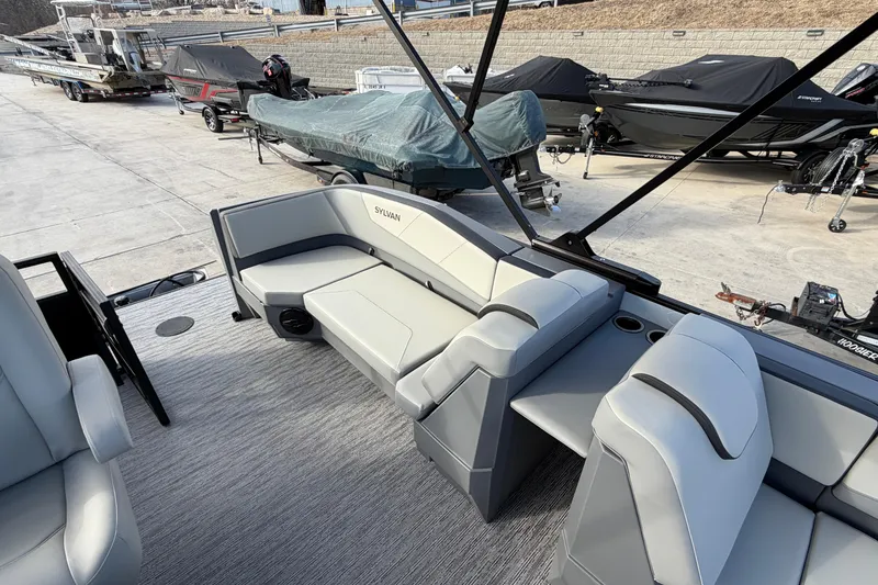 Slide: The Image of 2026 Sylvan A-18 boat interior with gray seating and covered boats in the background. - 8