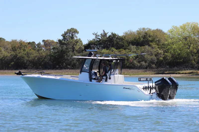 Slide: The Image of 2024 Front Runner 33 Center Console boat cruising on open water near a sandy shoreline. - 4