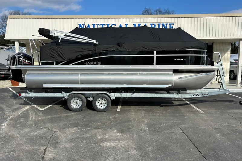 Slide: The Image of 2026 Harris Cruiser 210 pontoon boat on trailer, covered, outside Nautical Marine store. - 19