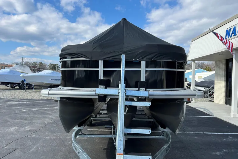 Slide: The Image of 2026 Harris Cruiser 210 pontoon boat on trailer, covered, in dealership lot. - 21