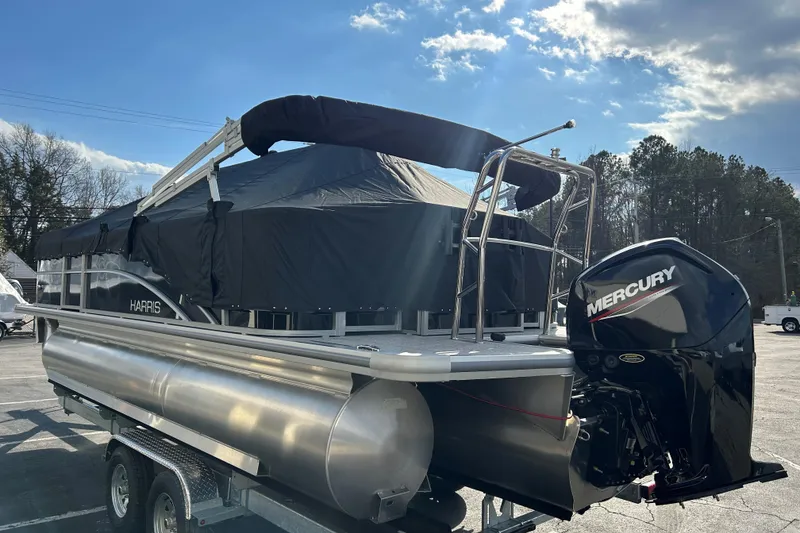 Slide: The Image of 2026 Harris Cruiser 210 pontoon boat with Mercury engine, parked outdoors under a sunny sky. - 23