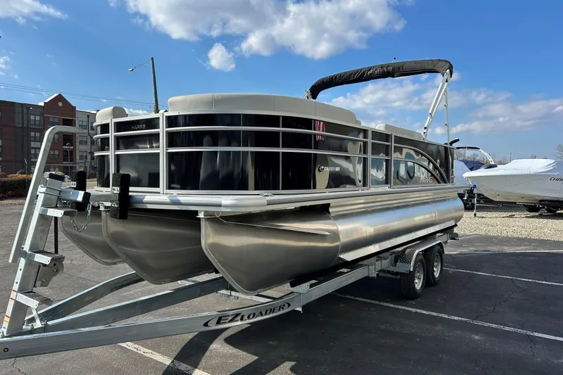 Slide: The Image of 2026 Harris Cruiser 210 pontoon boat on trailer under blue sky. - 3