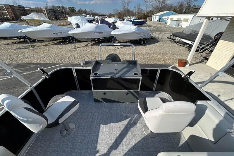 Slide: The Image of 2026 Harris Cruiser 210 boat interior with seating, docked near covered boats. - 8