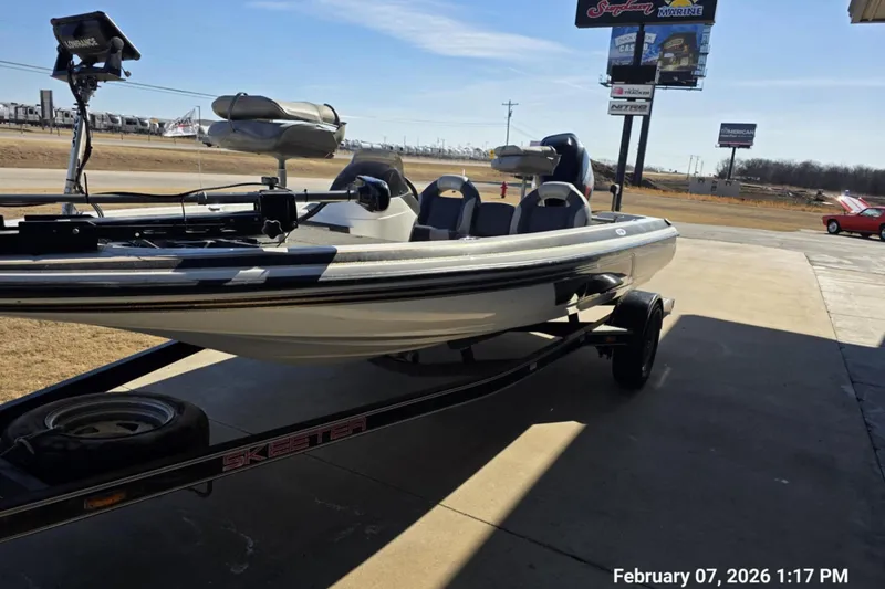 Slide: The Image of 2000 Skeeter SX180 boat on trailer, parked outdoors near a marine store. - 3