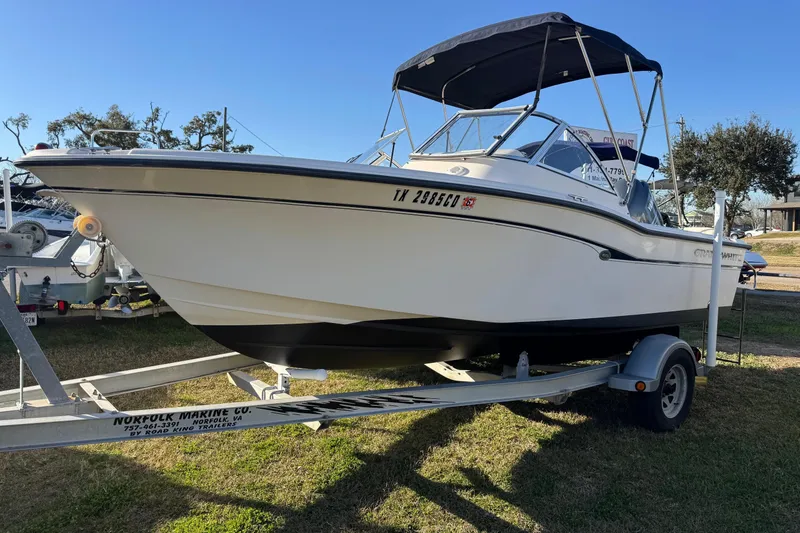 Slide: The Image of 2006 Grady-White Tournament 185 boat on trailer, parked on grass under clear blue sky. - 4