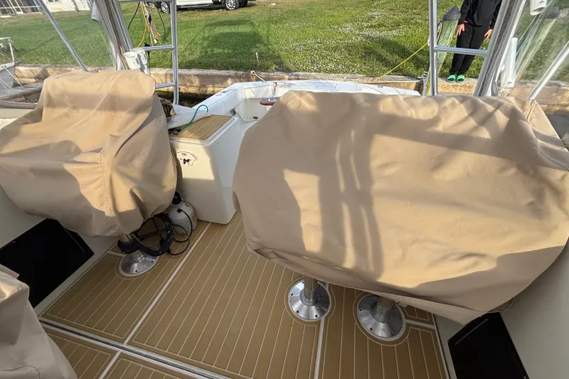 Slide: The Image of 2003 Carolina Classic 28 boat interior with covered seats and wooden flooring. - 14