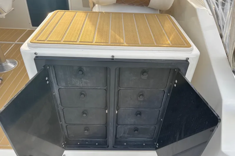 Slide: The Image of 2003 Carolina Classic 28 boat storage compartment with open doors and wooden top. - 22