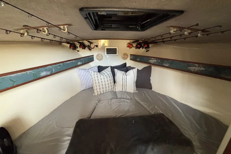 Slide: The Image of Cozy cabin interior of 2003 Carolina Classic 28 boat with fishing rods and pillows. - 35