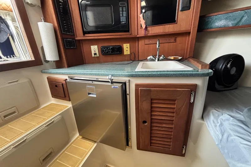 Slide: The Image of 2003 Carolina Classic 28 boat interior with kitchenette, featuring sink, microwave, and mini fridge. - 40