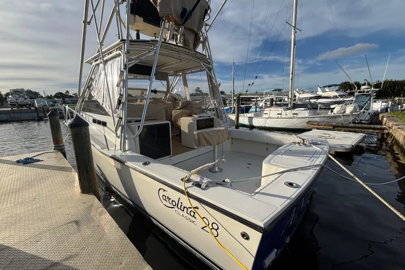 Slide: The Image of 2003 Carolina Classic 28 boat docked at a marina under a partly cloudy sky. - 8