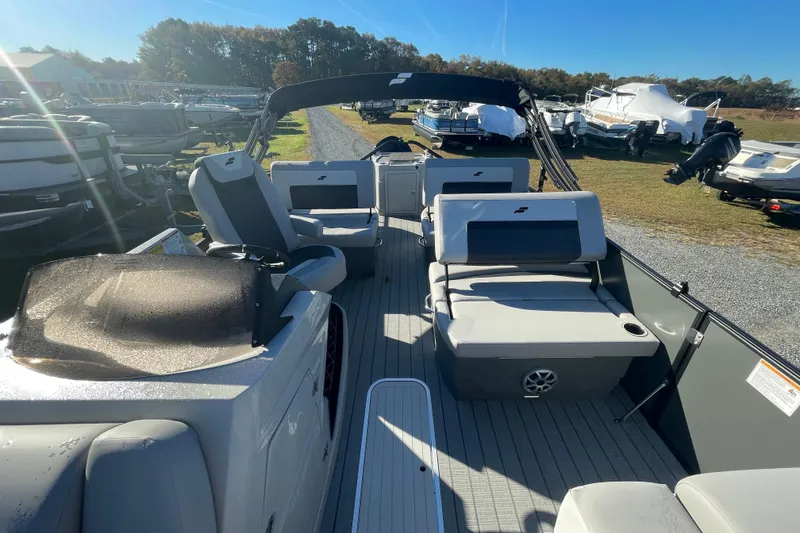Slide: The Image of 2026 Starcraft SLS 3 RL pontoon boat interior with seating and helm, parked outdoors. - 16