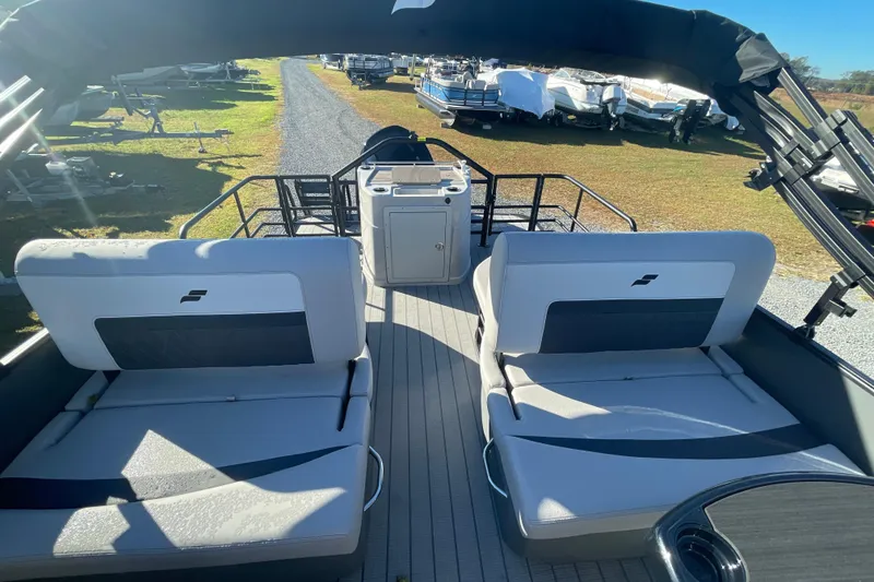 Slide: The Image of 2026 Starcraft SLS 3 RL pontoon boat interior with seating and helm, parked outdoors. - 17
