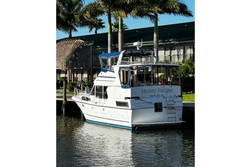 The Image of 1986 Heritage East Sundeck yacht docked, named "Honey Badger," in a tropical setting. - 0