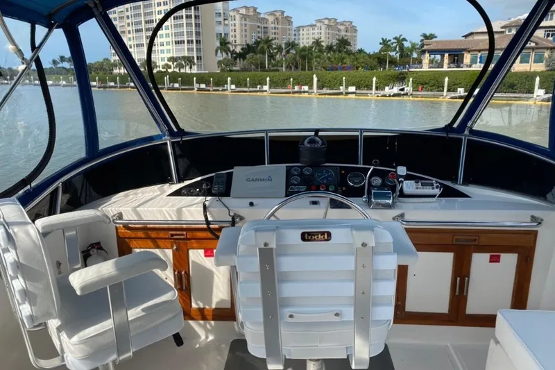 Slide: The Image of 1986 Heritage East Sundeck yacht helm with modern navigation equipment, docked near luxury buildings. - 10