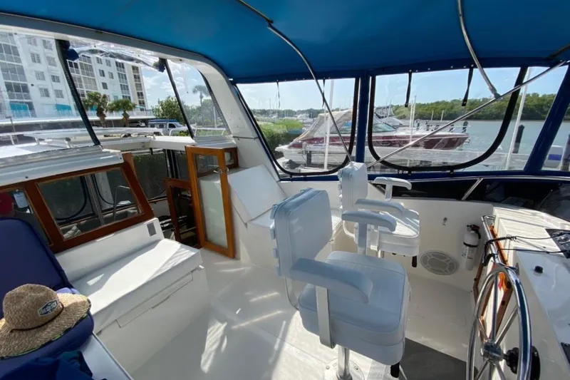 Slide: The Image of 1986 Heritage East Sundeck boat interior with helm, seating, and marina view. - 12