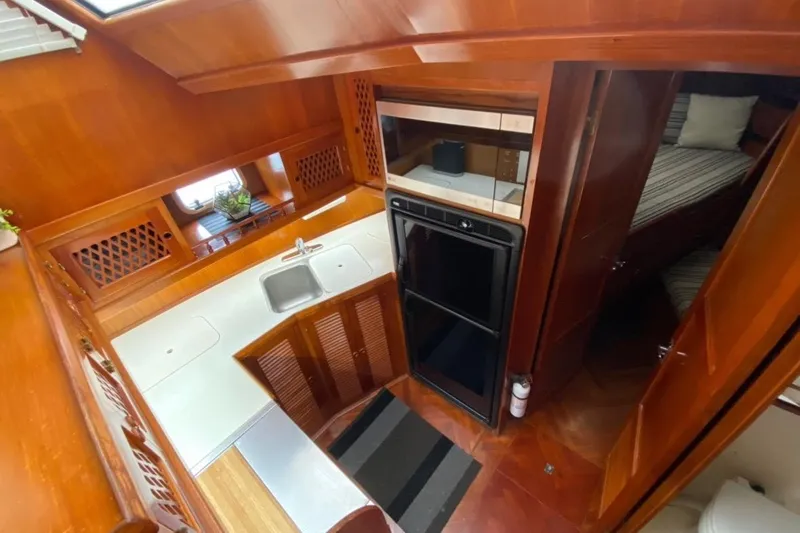 Slide: The Image of 1986 Heritage East Sundeck yacht interior with wooden cabinetry, kitchen sink, and cozy sleeping area. - 26