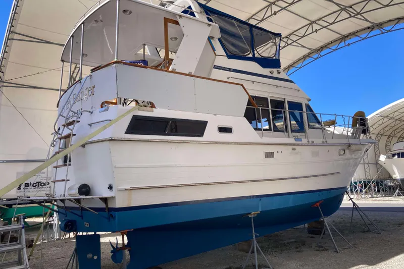 Slide: The Image of 1986 Heritage East Sundeck boat in dry dock under a canopy, side view. - 4