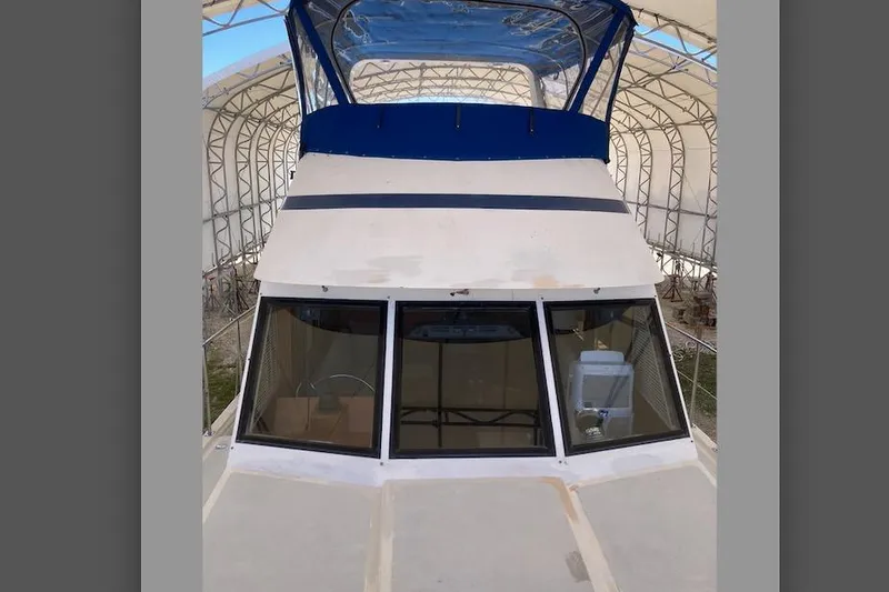 Slide: The Image of 1986 Heritage East Sundeck boat under a covered structure, featuring a blue canopy. - 7