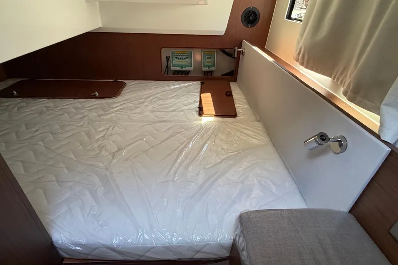 Slide: The Image of 2026 Beneteau Antares 9 cabin interior with bed, wood paneling, and window. - 21