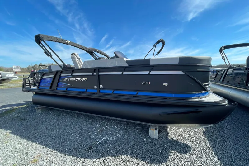 The Image of 2026 Starcraft SLS 1 pontoon boat with sleek black and blue design under clear sky. - 0