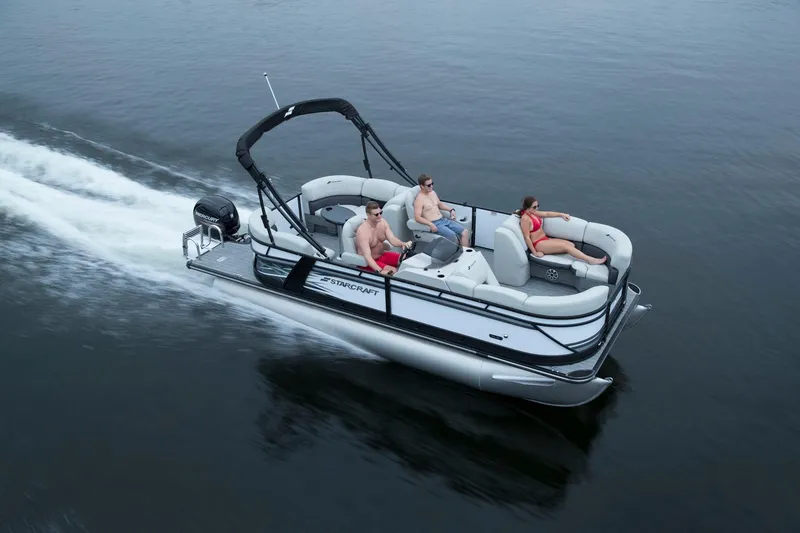 The Image of 2026 Starcraft SLS 1 pontoon boat cruising on water with passengers relaxing. - 1