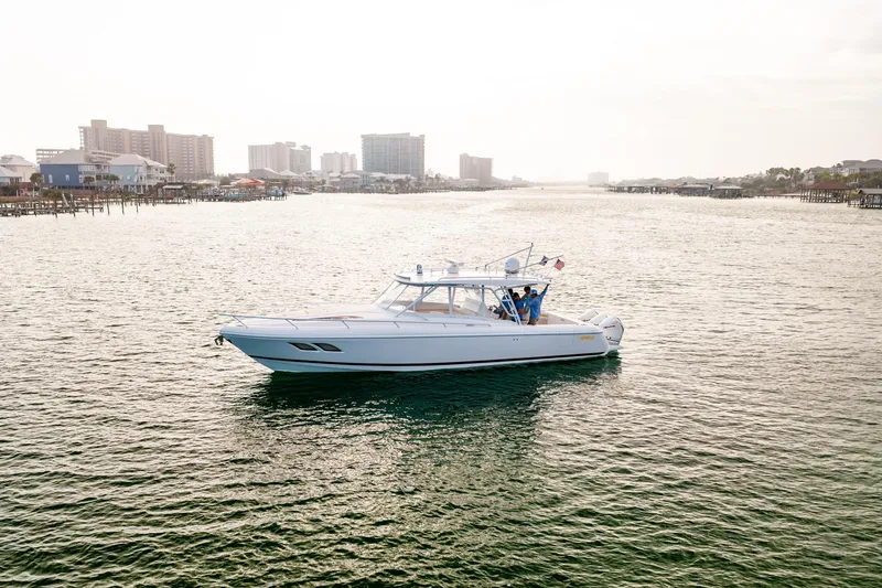 Slide: The Image of 2020 Intrepid 407 Cuddy boat cruising near a coastal residential area. - 11