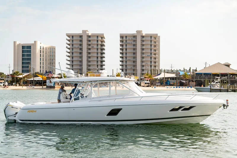 Slide: The Image of 2020 Intrepid 407 Cuddy boat cruising near modern beachfront buildings. - 5