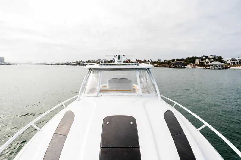 Slide: The Image of 2020 Intrepid 407 Cuddy boat cruising on calm waters near coastal homes. - 54