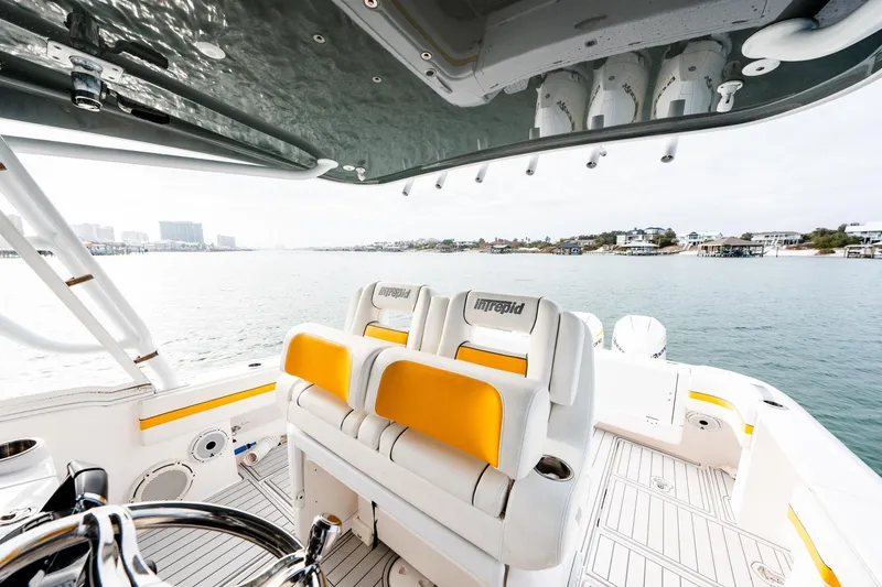 Slide: The Image of 2020 Intrepid 407 Cuddy boat interior with yellow-accented seating, overlooking calm waters. - 66