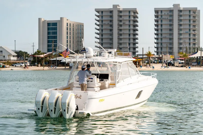 Slide: The Image of 2020 Intrepid 407 Cuddy boat cruising near modern beachfront buildings. - 7